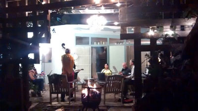 Several musicians, including a stand-up bass, on an outdoor patio at night.